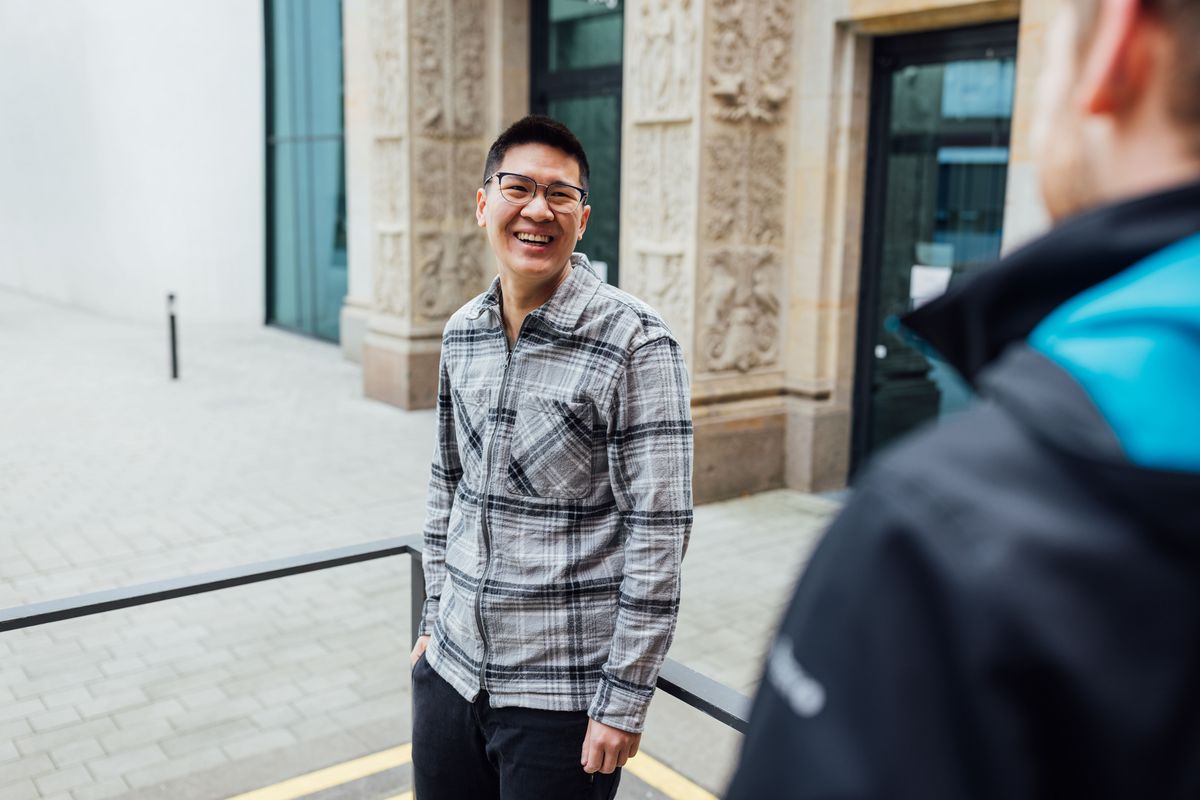 zur Vergrößerungsansicht des Bildes: Studienbotschafter Tuan steht auf dem Campus und lächelt, Foto: Christian Hüller