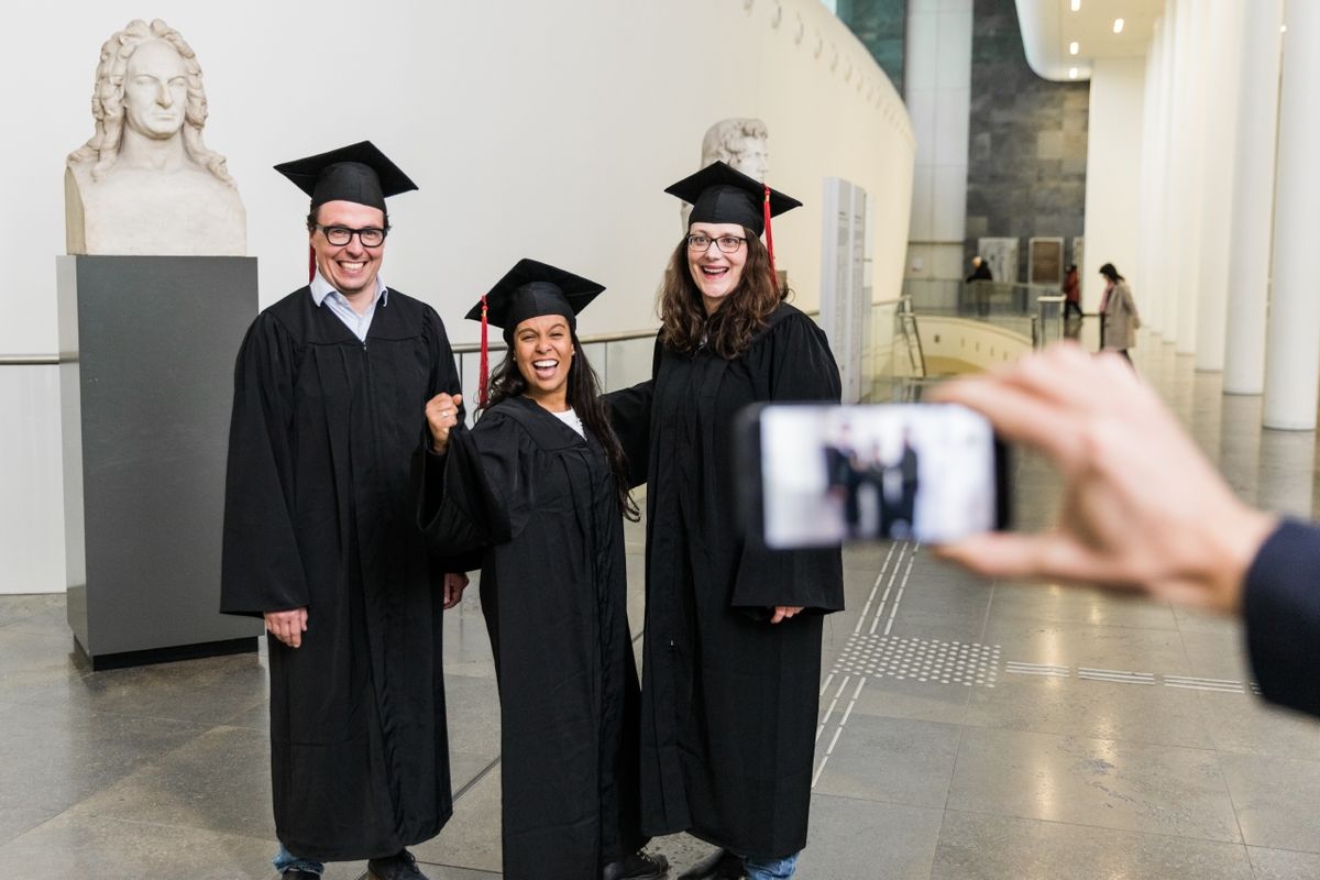 zur Vergrößerungsansicht des Bildes: Drei Alumni werden im Neuen Augusteum mit dem Smartphone fotografiert