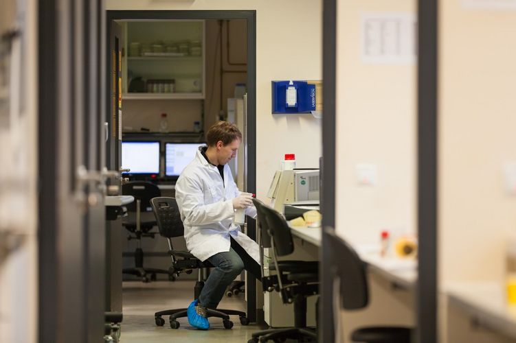 Student sitzt mit weißen Kittel im Labor und arbeitet, Foto: Christian Hüller
