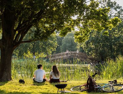 Junge und Mädchen sitzen am Ufer im Park, Foto: Christian Hüller