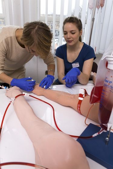 Studierende üben die Blutabnahme an einer Übungspuppe, Foto: Christian Hüller