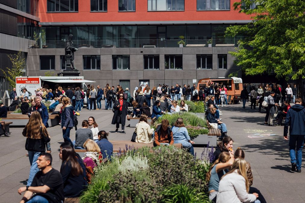 zur Vergrößerungsansicht des Bildes: Foto: Blick auf den Innenhof des Leibniz Forums. Man sieht Besuchspersonen und Food Trucks.