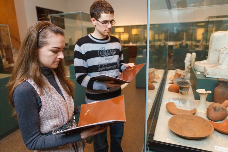 Zwei Studierende stehen vor Schaukästen und schauen in zwei Bücher, Foto: Christian Hüller