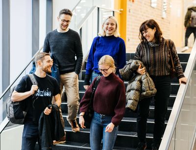 Studienbotschafterinnen und Studienbotschafter laufen gemeinsam die Treppe runter und lächeln, Foto: Christian Hüller