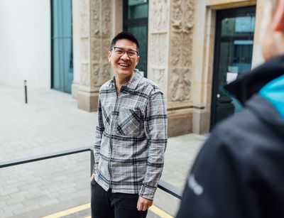 Studienbotschafter Tuan steht auf dem Campus und lächelt, Foto: Christian Hüller