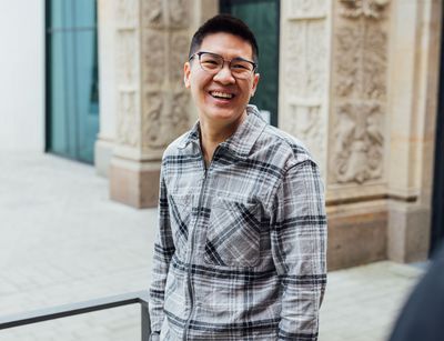 Studienbotschafter Tuan steht auf dem Campus und lächelt, Foto: Christian Hüller
