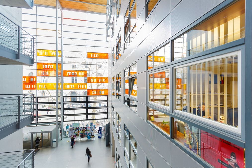 Sicht von oben auf das Foyer des Geisteswissenschaftlichen Zentrums und seiner Glassfassade mit bunten Elementen