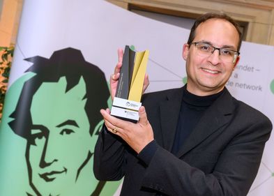 Professor Daniel Kráľ mit einer Art Pokal der Humboldt-Stiftung in den Händen.