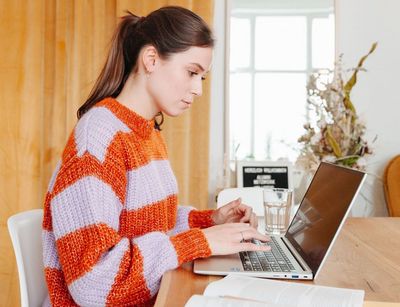 Junge Frau sitzt am Schreibtisch, vor ihr steht ein aufgeklappter Laptop, Foto: Grit Hartung