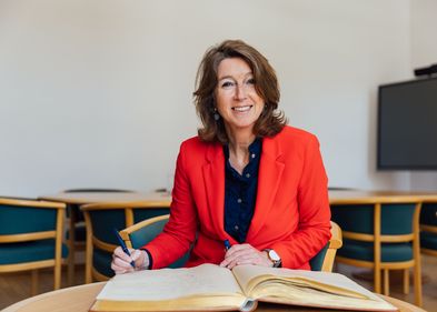 Hester Somsen, Botschafterin Seiner Majestät des Königs der Niederlande in Berlin, sitzt vor dem Goldenen Buch, einen Stift in der Hand.