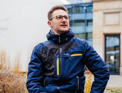 Studienbotschafter Sebastian sitzt auf dem Campus und spricht mit einem Studenten, Foto: Christian Hüller