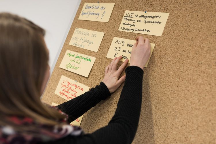 Eine Studentin hängt Karten zum Thema "Qualität der Sprachförderung" an eine Pinnwand, Foto: Christian Hüller 
