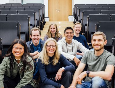 Gruppenbild Studienbotschafter:innen im Hörsaal auf dem Boden sitzend, Foto: Christian Hüller
