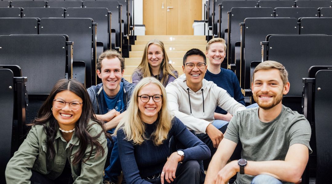 Gruppenbild Studienbotschafter:innen im Hörsaal auf dem Boden sitzend, Foto: Christian Hüller