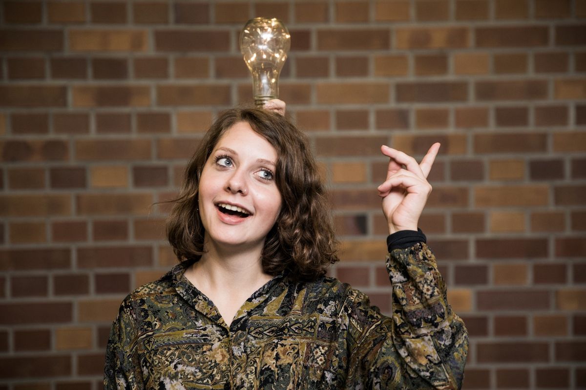 zur Vergrößerungsansicht des Bildes: Studentin vor Wand mit Glühbirne über dem Kopf, Foto: Christian Hüller