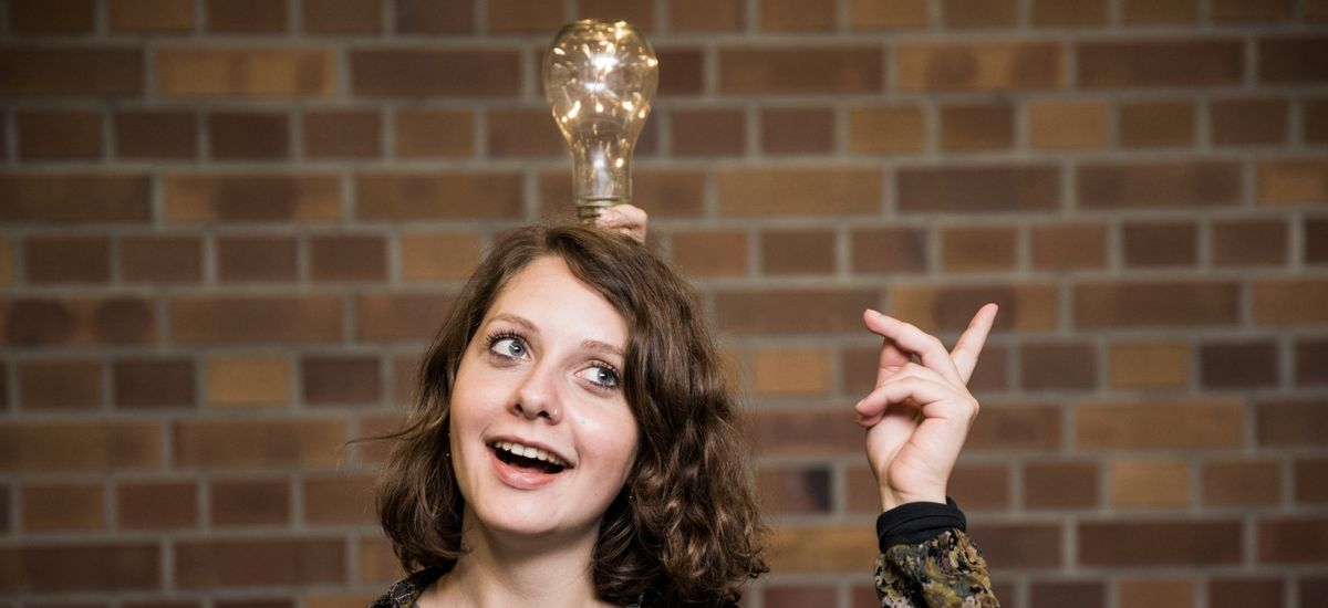 Studentin vor Wand mit Glühbirne über dem Kopf, Foto: Christian Hüller