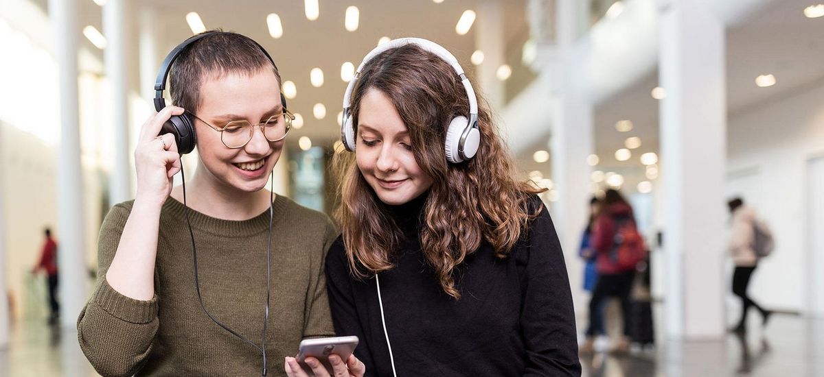 Zwei Studentinnen mit großen Kopfhörern hören in Neuen Augusteum der Uni Leipzig den neuen Podcast "Auf einen Kaffee mit...", Foto: Christian Hüller