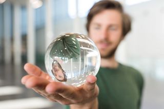 Student hält eine Glaskugel in der Hand und schaut hinein, Foto: Christian Hüller