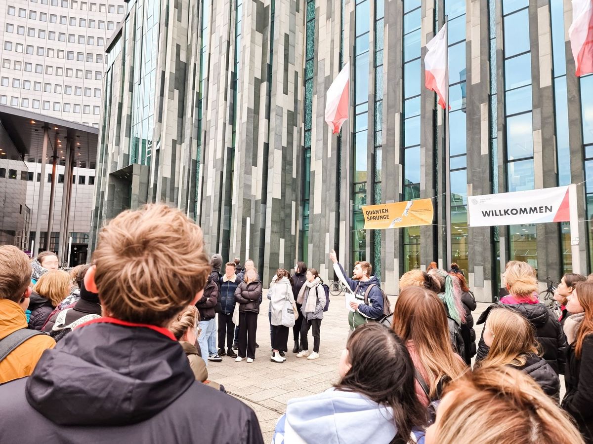 zur Vergrößerungsansicht des Bildes: Ein Campusführer steht mit einer Gruppe vor dem Neuen Augusteum