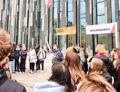 Ein Campusführer steht mit einer Gruppe vor dem Neuen Augusteum