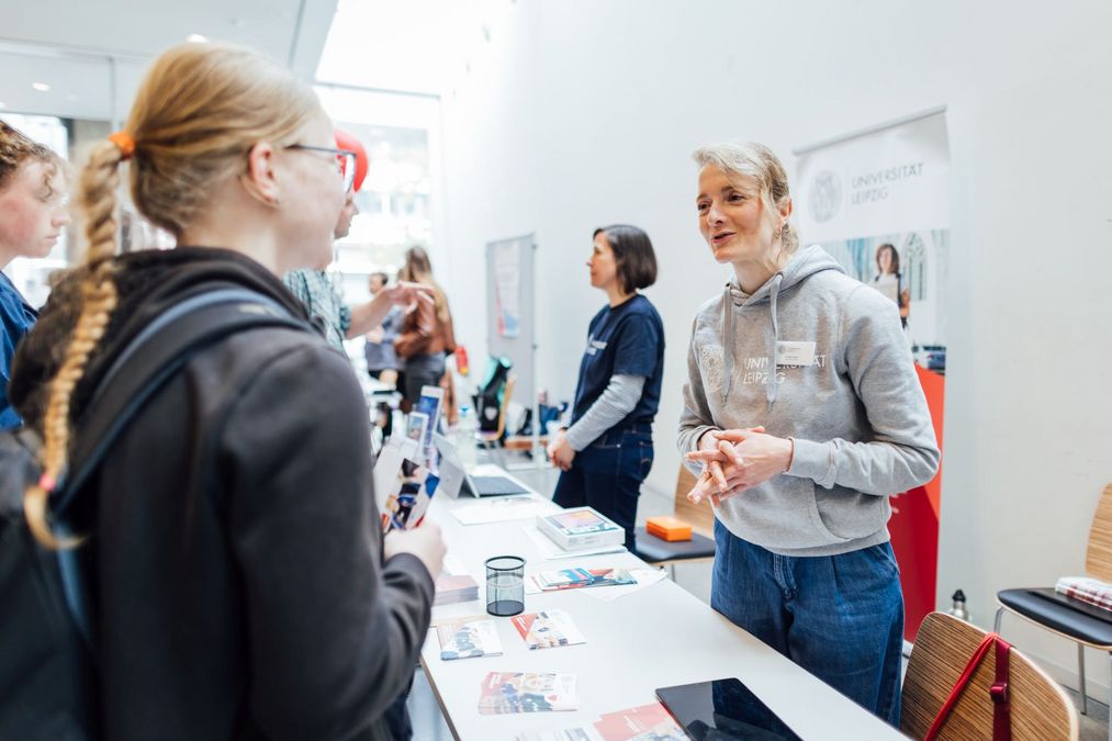 zur Vergrößerungsansicht des Bildes: Foto: Studienberaterin am Infostand der Zentralen Studienberatung im Gespräch mit einer Besucherin.