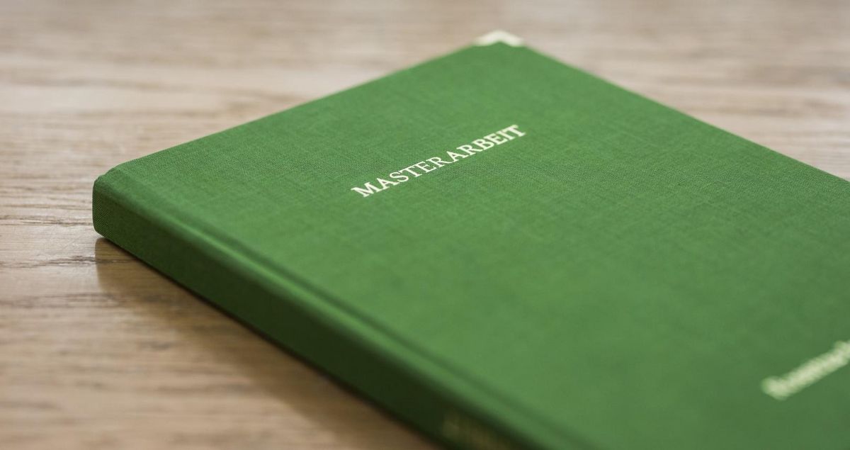 zur Vergrößerungsansicht des Bildes: Grünes Buch mit dem Titel Masterarbeit liegt geschlossen auf dem Tisch, Foto: Christian Hüller