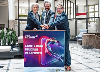 Rektorin Obergfell, Minister Gemkow und Rektor Kratzsch stehen an einem Tresen mit der Aufschrift "Starte dein Studium in Sachsen".